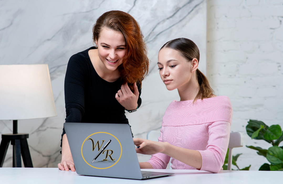 Two women sit at a laptop together planning a content strategy for their small business. 