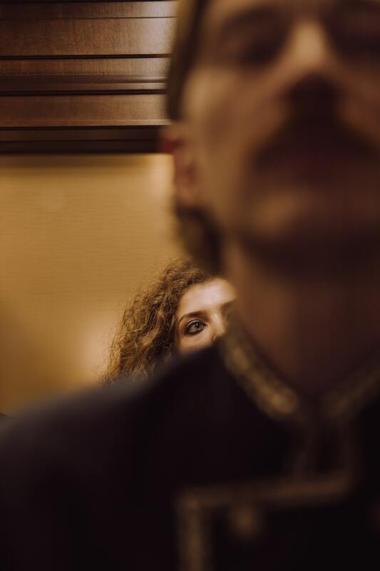 Woman looking over the shoulder of a man in an elevator.