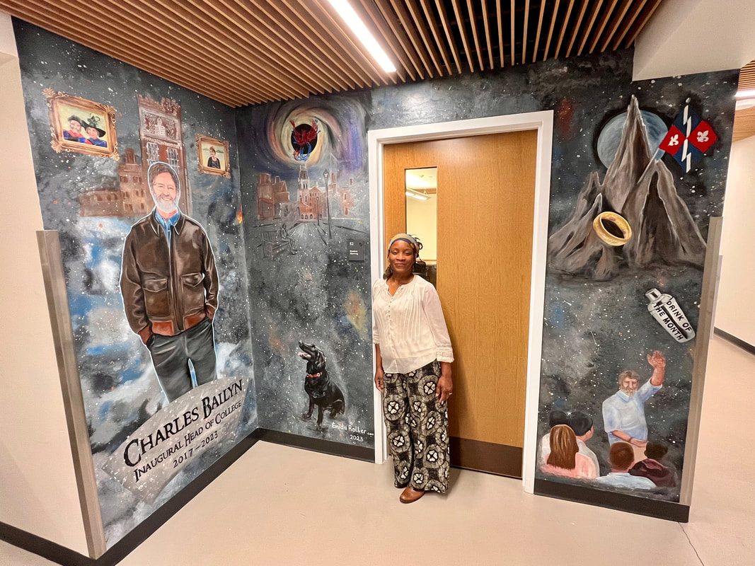Mural artist Emida Roller poses next to some of her interior wall art featuring Chearles Ballyn