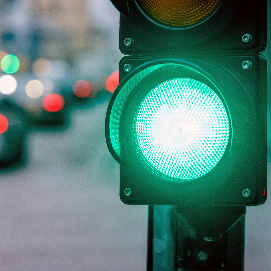 A green traffic light at an intersection. Traffic is blurred in the background. 