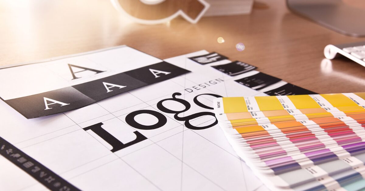 A color palette, logo design sketch, and other visual branding tools sit on a work desk.