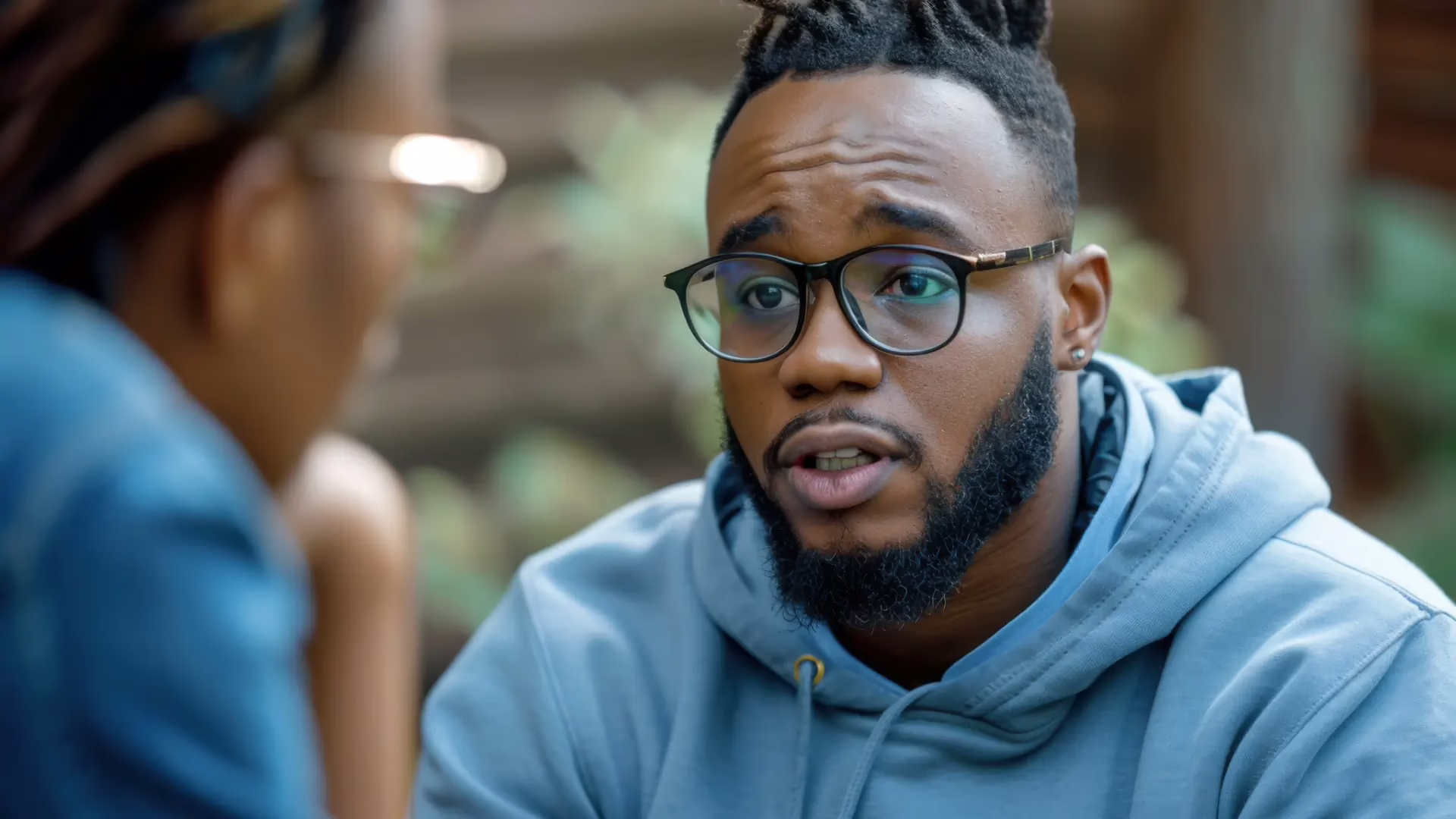 A Black man wearing glasses is having a sensitive conversation with a Black woman wearing glasses.