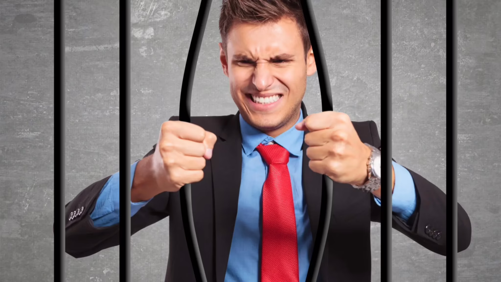 A man in a business suit tries to bend prison bars to get out. 
